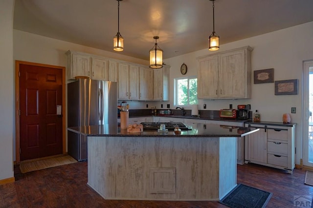 kitchen featuring appliances with stainless steel finishes, a kitchen island, dark wood finished floors, and pendant lighting