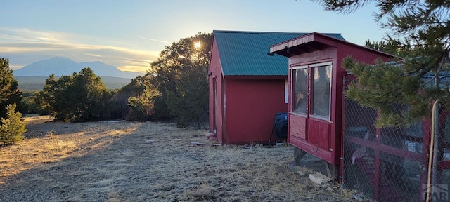 outdoor structure at dusk featuring an outbuilding, a mountain view, and exterior structure