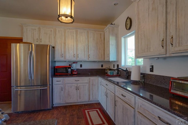 kitchen featuring pendant lighting, dark wood-type flooring, freestanding refrigerator, light brown cabinets, and a sink