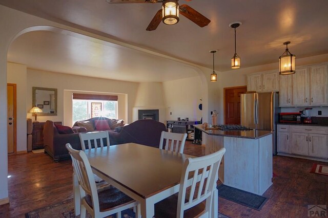 dining space featuring dark wood-style floors, arched walkways, and a ceiling fan