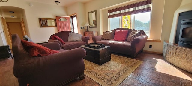 living room with dark wood-type flooring, arched walkways, and baseboards
