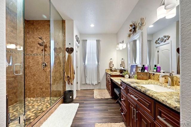 bathroom with a stall shower, baseboards, wood finished floors, and vanity