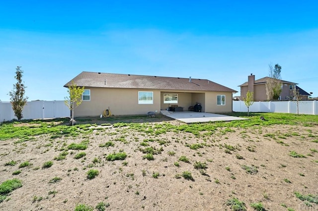 rear view of house with stucco siding, a fenced backyard, and a patio