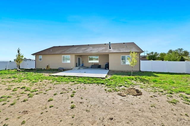 rear view of property featuring a patio area, a fenced backyard, a yard, and stucco siding