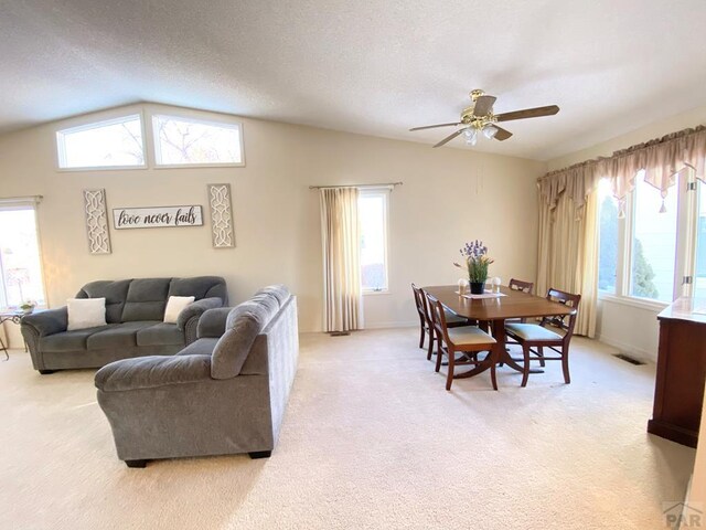 living area featuring a wealth of natural light, light colored carpet, visible vents, and vaulted ceiling