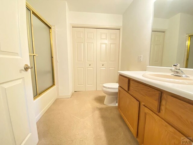 bathroom with carpet floors, bath / shower combo with glass door, a closet, toilet, and vanity