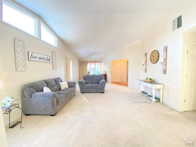 living room featuring plenty of natural light, carpet, visible vents, and high vaulted ceiling