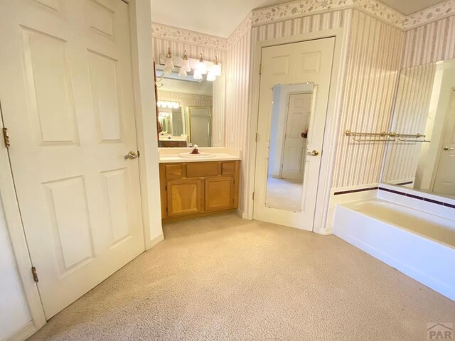 full bath with vanity, carpet flooring, a bath, and wallpapered walls