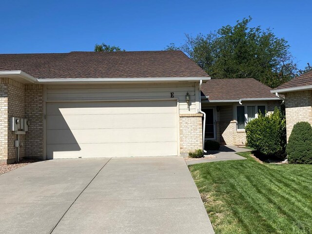 single story home featuring a garage, concrete driveway, brick siding, and a front yard