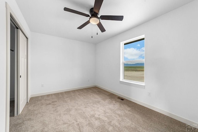 unfurnished bedroom with carpet flooring, visible vents, baseboards, a ceiling fan, and a closet