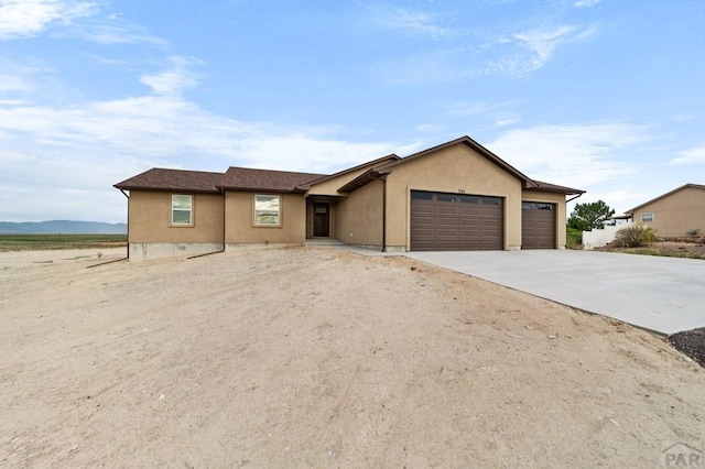 single story home with stucco siding, concrete driveway, and a garage