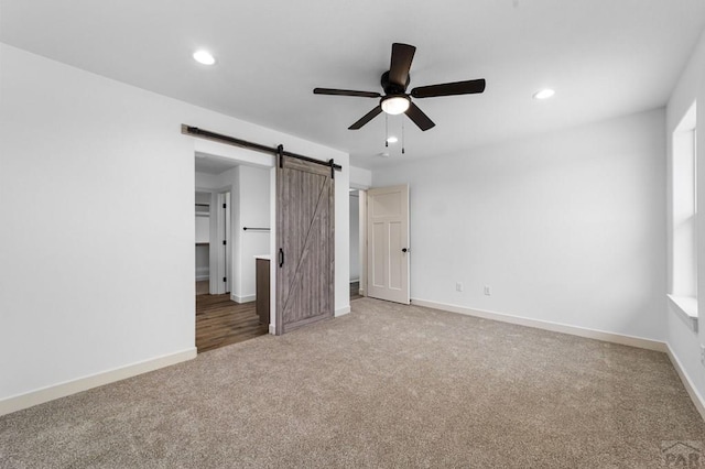 unfurnished bedroom featuring a barn door, carpet flooring, baseboards, and recessed lighting