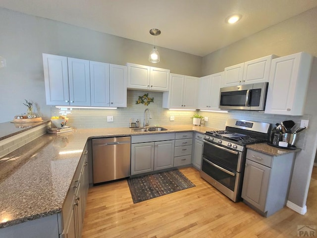 kitchen featuring a sink, white cabinetry, appliances with stainless steel finishes, backsplash, and pendant lighting