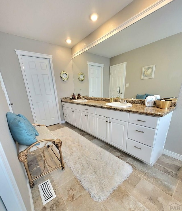 full bath with visible vents, a sink, baseboards, and double vanity