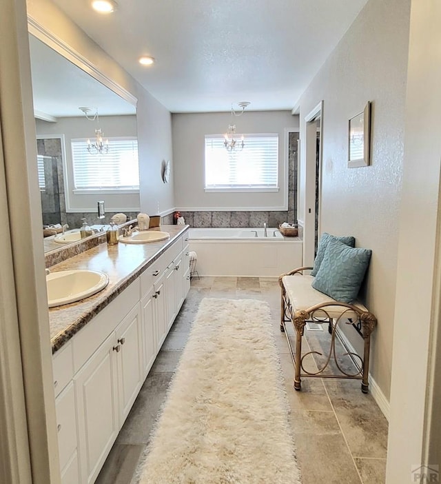 full bathroom featuring a sink, a garden tub, plenty of natural light, and a notable chandelier