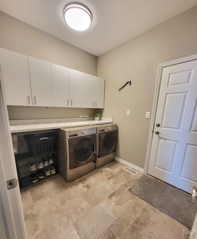 clothes washing area with cabinet space, visible vents, baseboards, and separate washer and dryer