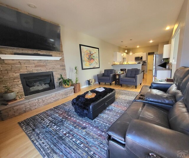 living area featuring a stone fireplace and light wood-style flooring