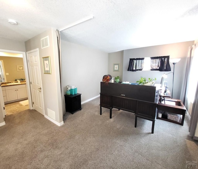 office space featuring baseboards, visible vents, a textured ceiling, and light colored carpet