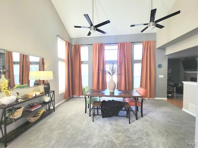 carpeted dining room with baseboards, high vaulted ceiling, and a wealth of natural light