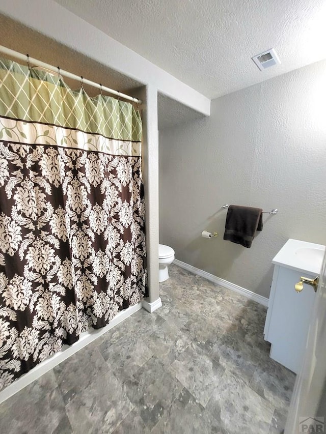 full bath featuring a textured ceiling, toilet, vanity, visible vents, and baseboards