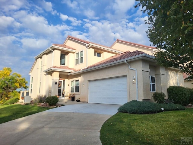 mediterranean / spanish house featuring a front yard, a tile roof, driveway, and stucco siding