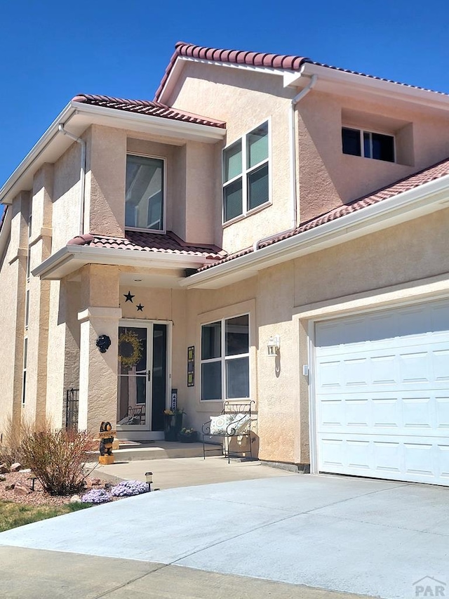 view of front of house with a tiled roof, concrete driveway, and stucco siding