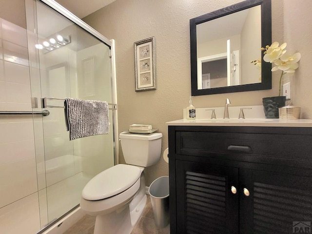 bathroom featuring a textured wall, a stall shower, vanity, and toilet