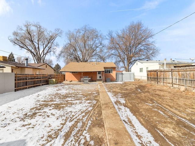 snow covered rear of property featuring fence, central AC, and stucco siding