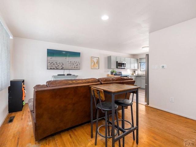 kitchen featuring stainless steel appliances, visible vents, light wood finished floors, and gray cabinetry