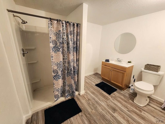 bathroom with a stall shower, toilet, wood finished floors, a textured ceiling, and vanity