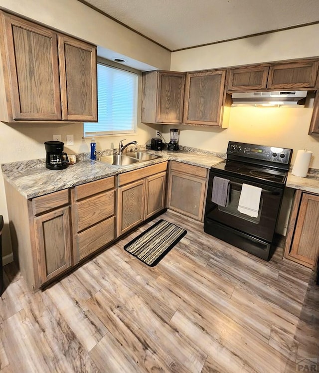 kitchen featuring light wood-style flooring, light stone counters, black range with electric stovetop, under cabinet range hood, and a sink