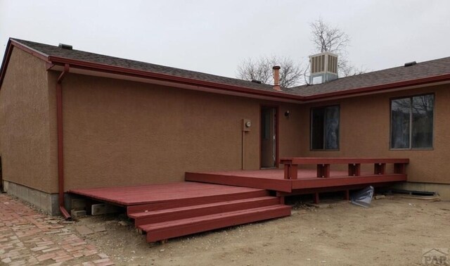 rear view of house featuring a shingled roof, a wooden deck, and stucco siding