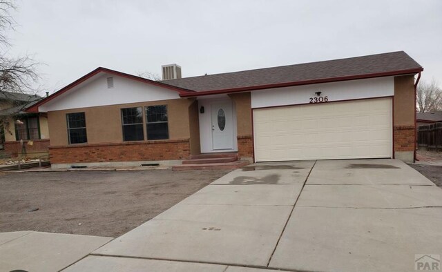 single story home featuring a garage, concrete driveway, and brick siding