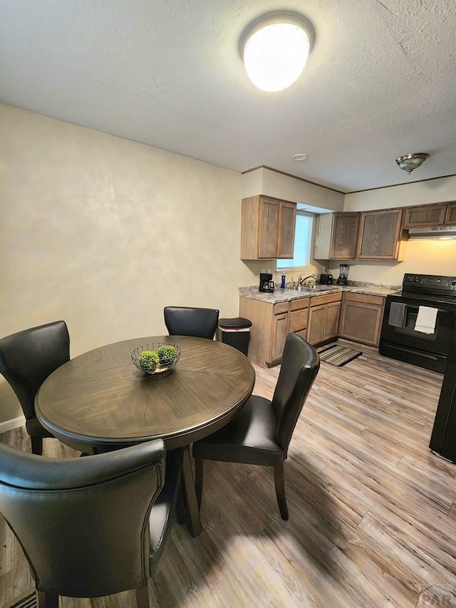 dining area featuring light wood finished floors and a textured ceiling