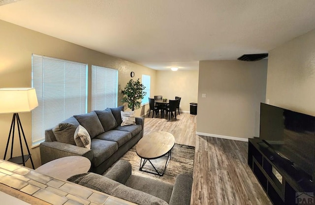 living room with wood finished floors, visible vents, and baseboards