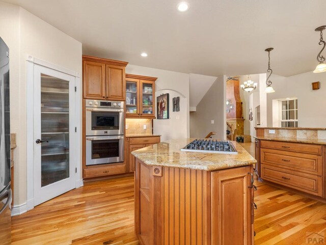 348 S Tejon Ln, Pueblo West, CO 81007 - kitchen featuring appliances with stainless steel finishes, brown cabinetry, light wood-style floors, a kitchen island, and recessed lighting