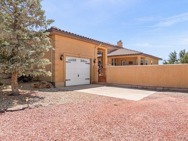 348 S Tejon Ln, Pueblo West, CO 81007 - view of front of house featuring a garage, a chimney, driveway, a tile roof, and a gate