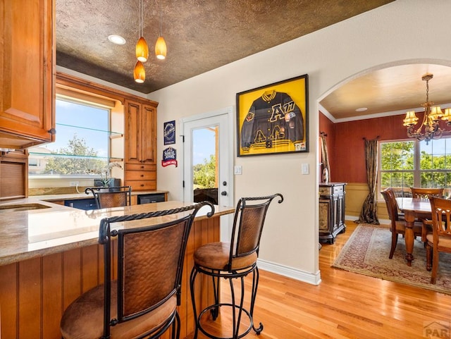 348 S Tejon Ln, Pueblo West, CO 81007 - kitchen with a chandelier, light wood finished floors, decorative light fixtures, and brown cabinets