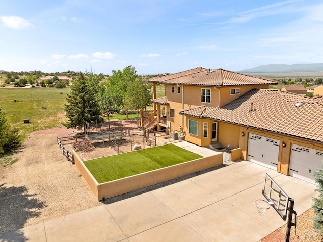 348 S Tejon Ln, Pueblo West, CO 81007 - view of front facade featuring stucco siding, a tiled roof, driveway, a garage, and a mountain view