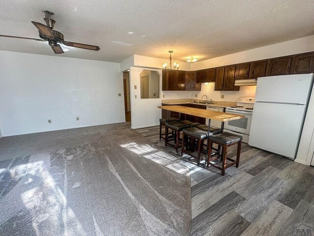kitchen featuring wooden counters, under cabinet range hood, dark brown cabinets, and white appliances