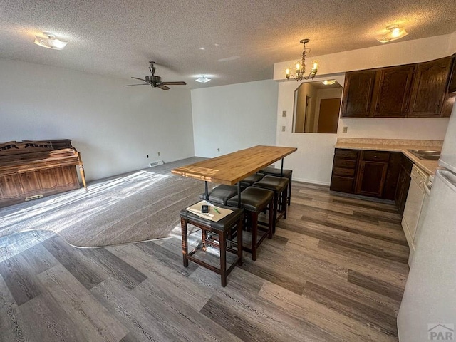 dining room with dark wood-style flooring, a textured ceiling, and ceiling fan with notable chandelier