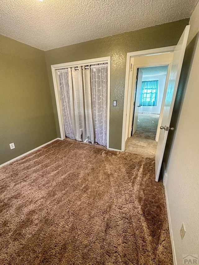 unfurnished bedroom with a textured wall, carpet, a closet, and a textured ceiling