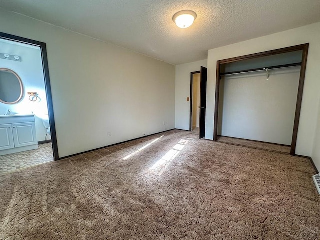 unfurnished bedroom with a closet, carpet floors, a sink, and a textured ceiling