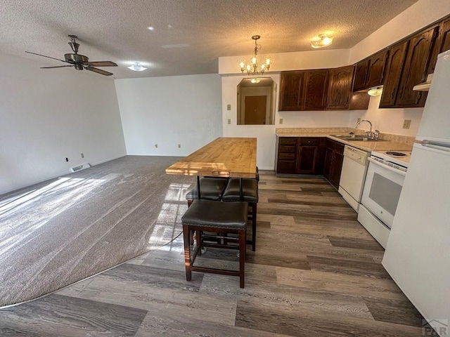 kitchen with light countertops, white appliances, ceiling fan with notable chandelier, a sink, and dark brown cabinets