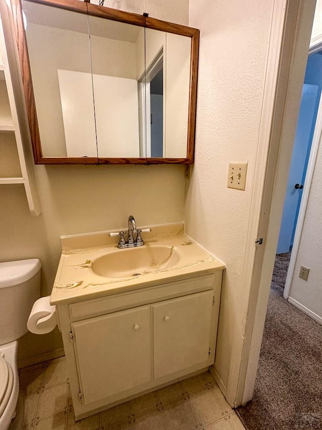 bathroom with toilet, vanity, tile patterned floors, and baseboards