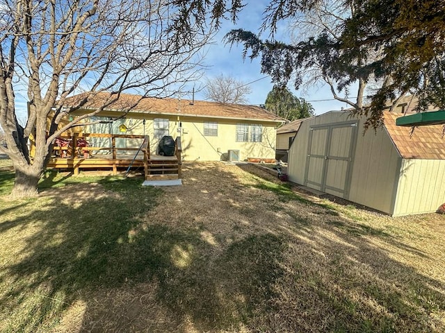 back of property featuring central air condition unit, a storage shed, a deck, an outbuilding, and a yard