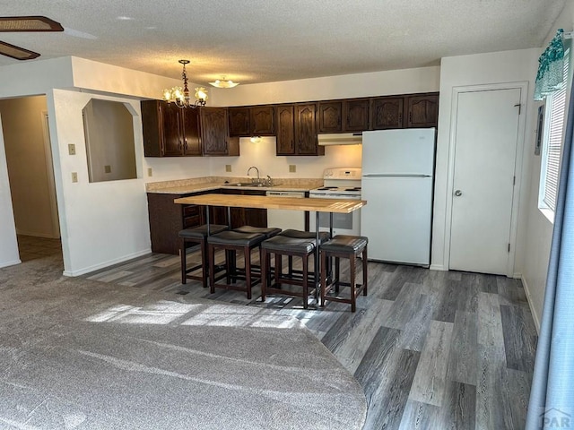 kitchen with dark brown cabinetry, a sink, a textured ceiling, under cabinet range hood, and white appliances