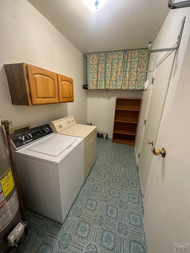 clothes washing area with cabinet space, gas water heater, washing machine and dryer, and a textured ceiling