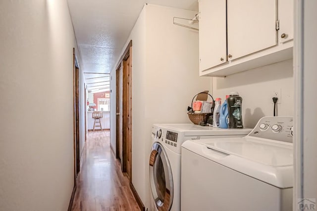 clothes washing area with cabinet space, washer and clothes dryer, and wood finished floors