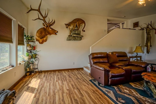 living area with baseboards, ceiling fan, and wood finished floors